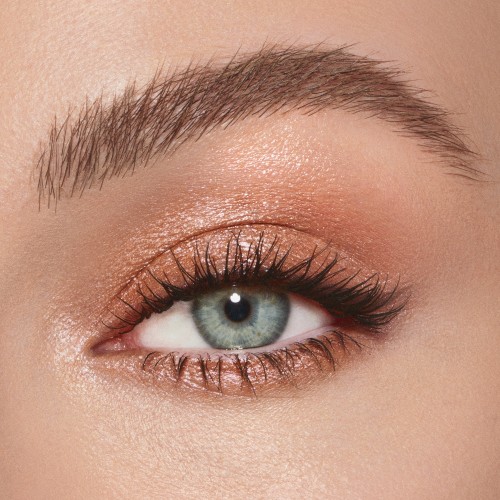 Single-eye close-up of a fair-tone model with blue eyes wearing a shimmering nude cream eyeshadow.