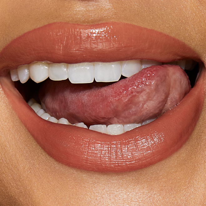 Lips close-up of a medium-tone model wearing a moisturising lipstick balm in a peachy-nude shade.