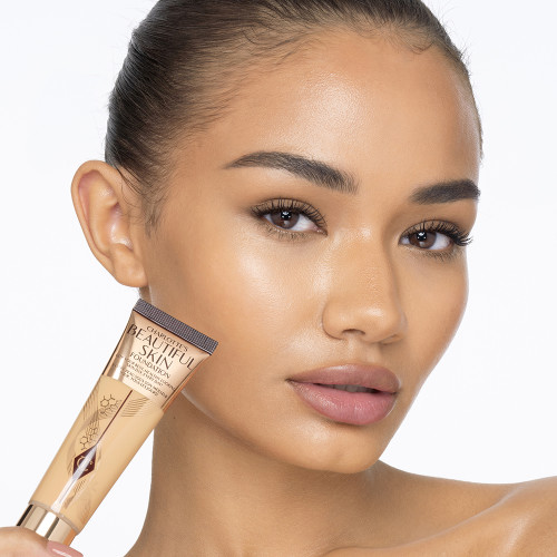 Deep-tone model with glowy, flawless skin, wearing skin-like foundation that adds a youthful glow and looks natural along with nude pink lipstick and subtle everyday eye makeup.