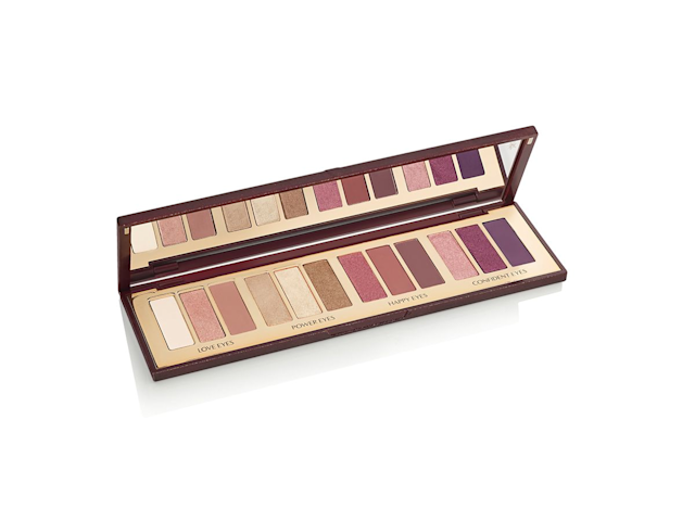 An open, mirrored-lid eyeshadow palette in matte and shimmery brown, pink, gold, purple, and nude shades. 