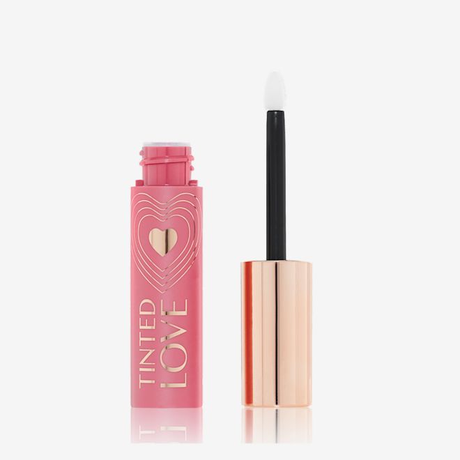 Emballage Tinted Love en teinte rose pétale An open lip and cheek tint in a rosy pink shade with a pink-coloured bottle with a white and gold-coloured doe-foot applicator.