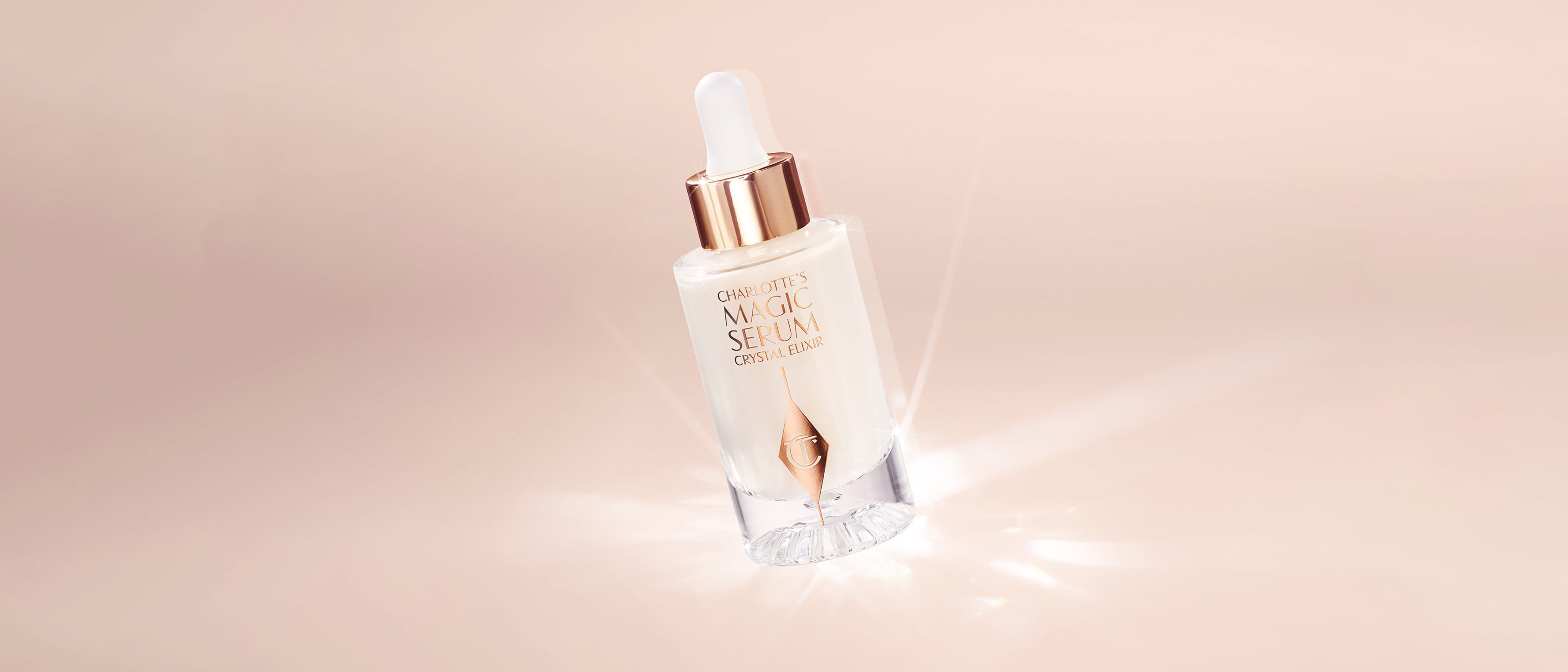 Charlotte's Magic Serum Crystal Elixir bottle on pale pink background