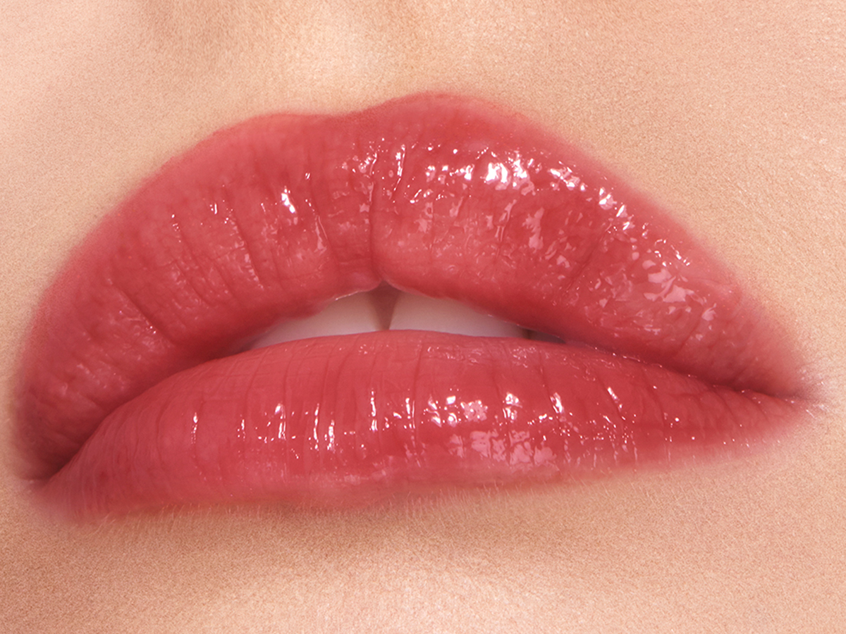 Lips close-up of a fair-tone model wearing a sheer berry-rose lip gloss.
