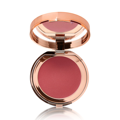 An open, mirrored-lid lip and cheek cream compact in a brownish-red shade.