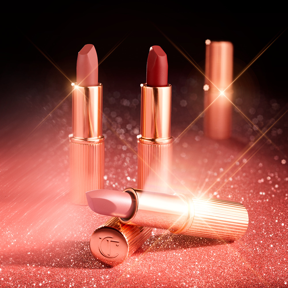 Three open, matte finish lipsticks in gold-coloured tubes in red, nude brown, and nude pink shades.