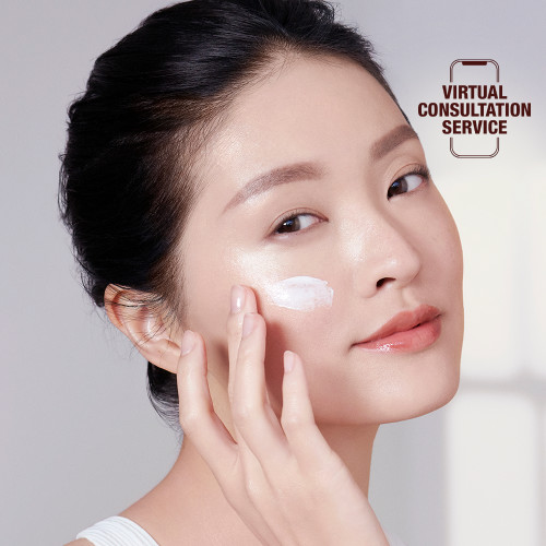 Fair-tone brunette model with flawless, glowy skin applying pearly-white face cream. 
