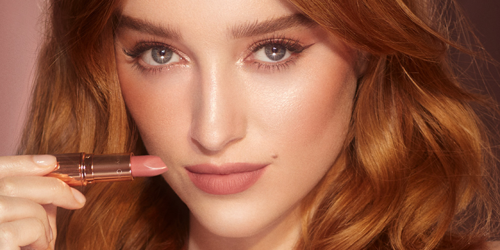 Light-tone model with blue eyes wearing smokey brown eye makeup, glowy nude pink blush, and nude pink matte lipstick. 