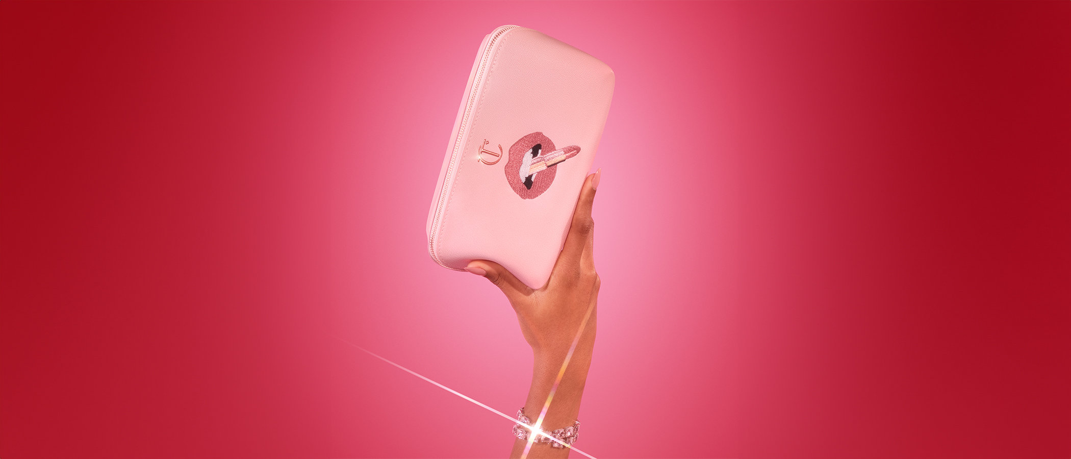 Hand holding a pink travel makeup bag with a lip design and CT emblem logo