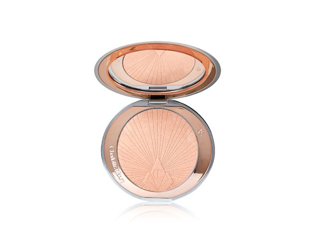  An open, pressed highlighter compact in a light pinky beige shade with a mirrored-lid.
