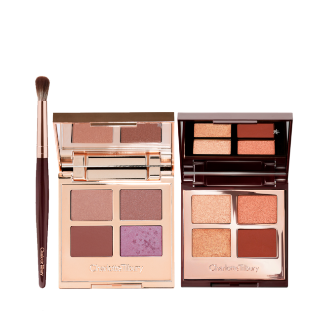 An eyeshadow blending brush and two, open quad eyeshadow palettes with mirrored lids, both with matte and shimmery eyeshadows in shades of nude beige, brown, mud brown, violet, champagne, peach, gold, and clay-brown.