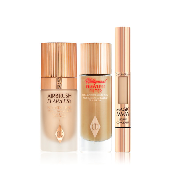 A glowy primer in a glass bottle with gold-coloured lid, foundation in a frosted glass bottle with gold-coloured lid, and creamy concealer in a gold-coloured tube. 