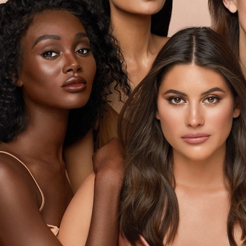 Medium and deep-tone models with flawless smooth skin and wearing nude pink lipstick with subtle, glowy blush, and smokey eye makeup.