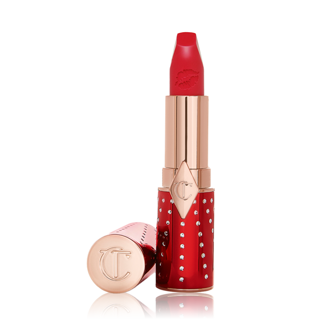 An open lipstick in a matte, bright cherry red shade in a red and gold-coloured tube.