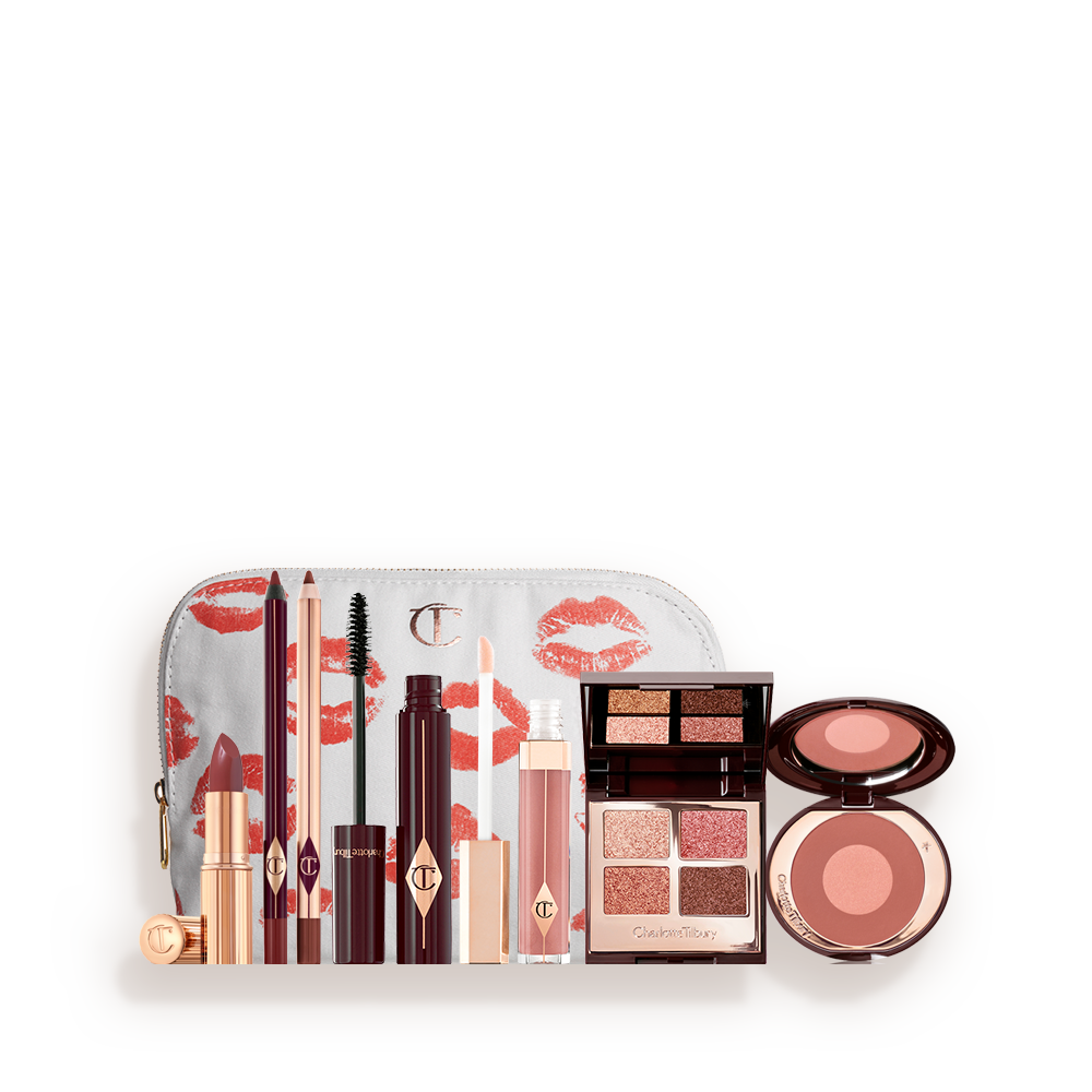 A white makeup pouch with open products displayed, which include a berry-rose lipstick, maroon eyeliner pen, berry-rose lip liner pencil, mascara, nude-pink lip gloss, a mirrored-lid quad eyeshadow palette, and a two-tone warm-pink blush. 