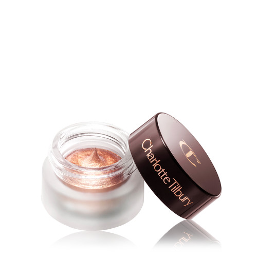 An open glass pot filled with shimmery cream eyeshadow in rose-gold shade with its lid next to it. 