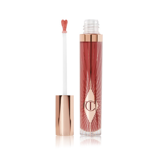A lip gloss in a berry-pink shade with its heart-shaped applicator next to it.