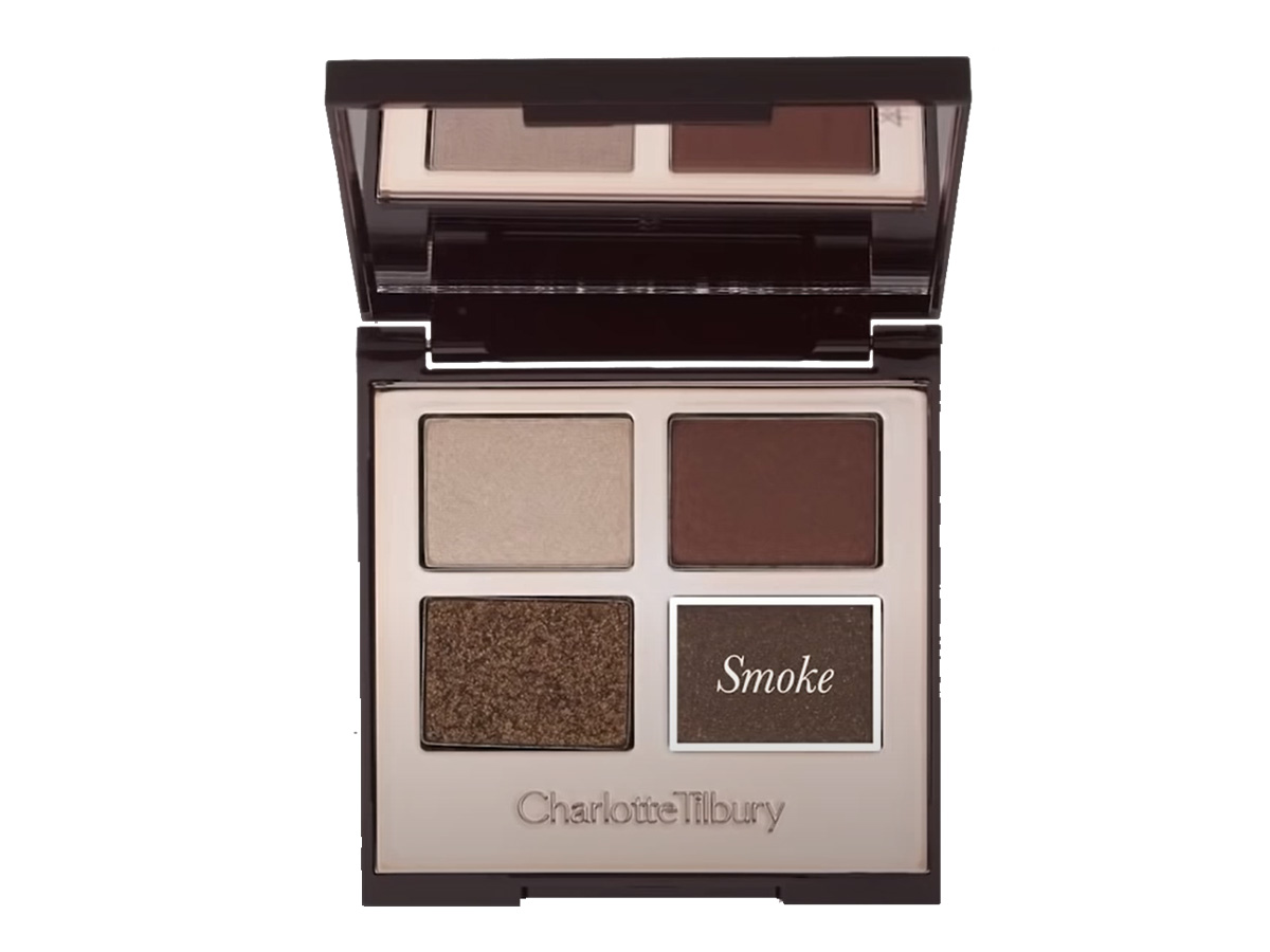 An open, mirrored-lid quad eyeshadow palette with eyeshadows in shades of shimmery brown, dark brown, grey-brown, and dark beige, with smoke written on the grey-brown shade. 