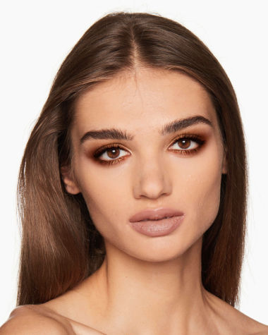 A medium-tone brunette model with brown eyes wearing shimmery, copper and gold eyeshadow with rust and copper-coloured eyeliner on the upper lid and lower waterline. 