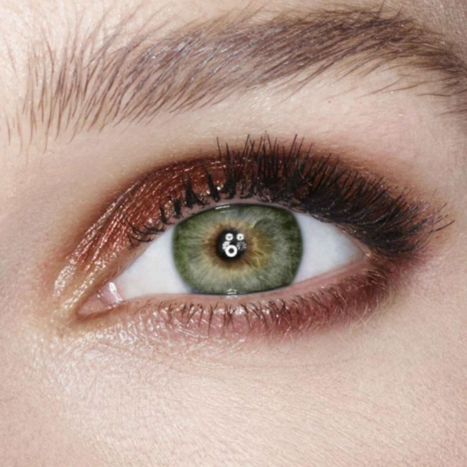 Single-eye close-up of a green-eyed model wearing shimmery reddish-bronze eyeshadow. 