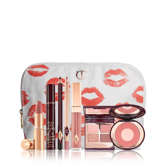 Pillow Talk look kit displayed with makeup pouch A mascara with an open, mirrored-lid quad eyeshadow palette in shimmery neutral shades, a shimmery nude pink lipstick, a nude pink lip gloss and lip liner pencil, and a two-tone powder blush compact in a bright pink shade, with all products in front of a white-coloured makeup pouch.