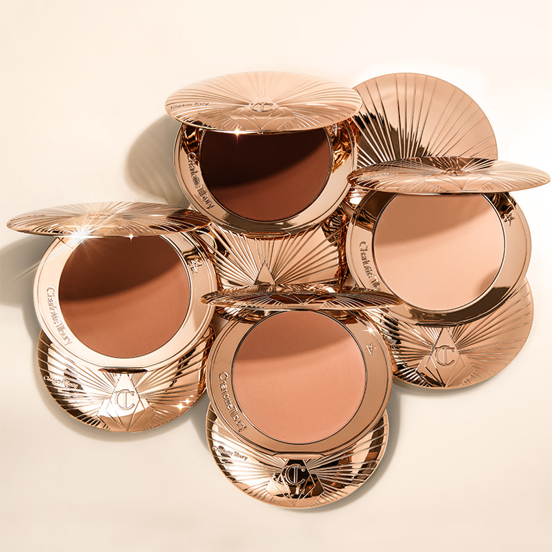 A collection of closed bronzer compacts with three open bronzer compacts in light, medium, and medium dark shades.