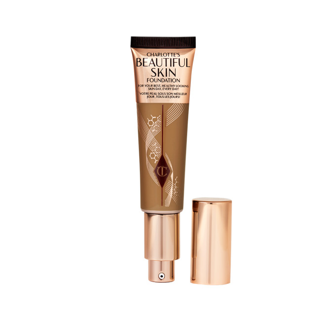 An open foundation wand in gold packaging with a pump dispenser and a dark-brown-coloured body to show the shade of the foundation inside. 