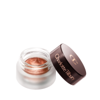 An open glass pot with shimmery russet rose cream eyeshadow with golden-peach sparkle and its lid placed next to it.