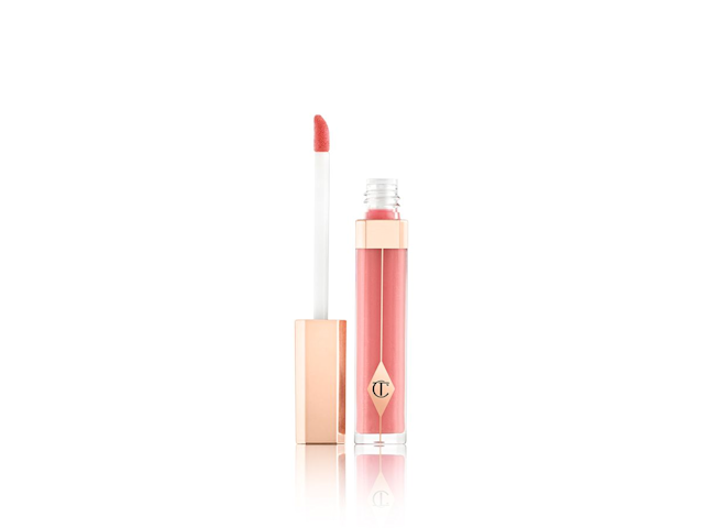 An open lip gloss in a peachy-pink colour with its doe foot applicator next to it. 