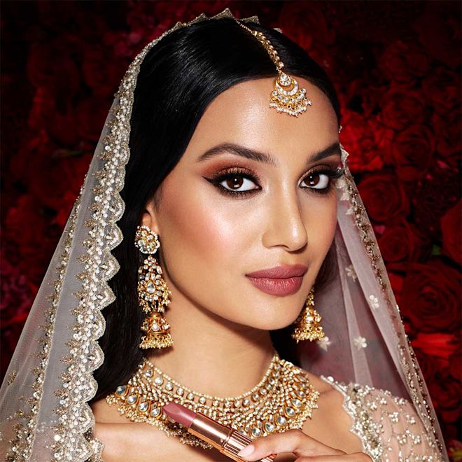 Mesmerising Indian Wedding look on medium-tone model Medium-tone model with brown eyes wearing glowy foundation with muted terracotta blush, dark berry-rose lipstick, kohl-lined eyes, and smokey berry-pink and brown eye makeup.