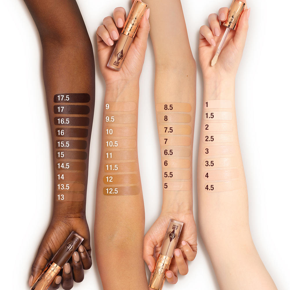 Four forearms displaying swatches of Charlotte Tilbury Airbrush Flawless Concealer shades from deep to fair, each arm holding a concealer tube with rose-gold cap.