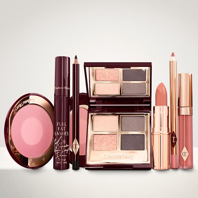 The Uptown Girl Look kit for light, fair and medium displayed An open, mirrored-lid eyeshadow palette in matte and shimmery gold and grey shades, an open black eyeliner pencil, a mascara in a dark-crimson colour scheme, a golden-peach lipstick with a matching lip liner pencil, coral lip gloss, and an open two-tone blush in cool pink.