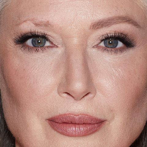 Before and after of a fair-tone model with grey eyes and mature skin with bare brows on one side and thick, filled, and lined eyebrows on the other side after applying a taupe-coloured eyebrow pencil.