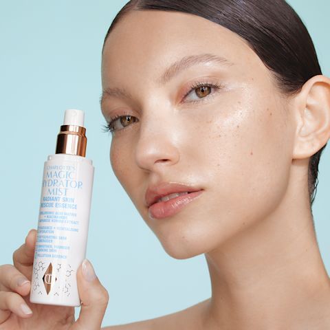 Edna holding Charlotte's Magic Hydrator Mist with the cap off