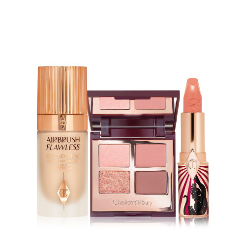 Foundation in a glass bottle with gold-coloured lid, open mirrored-lid quad eyeshadow palette with an open, nude peach lipstick in a funky tube with a panther on it.