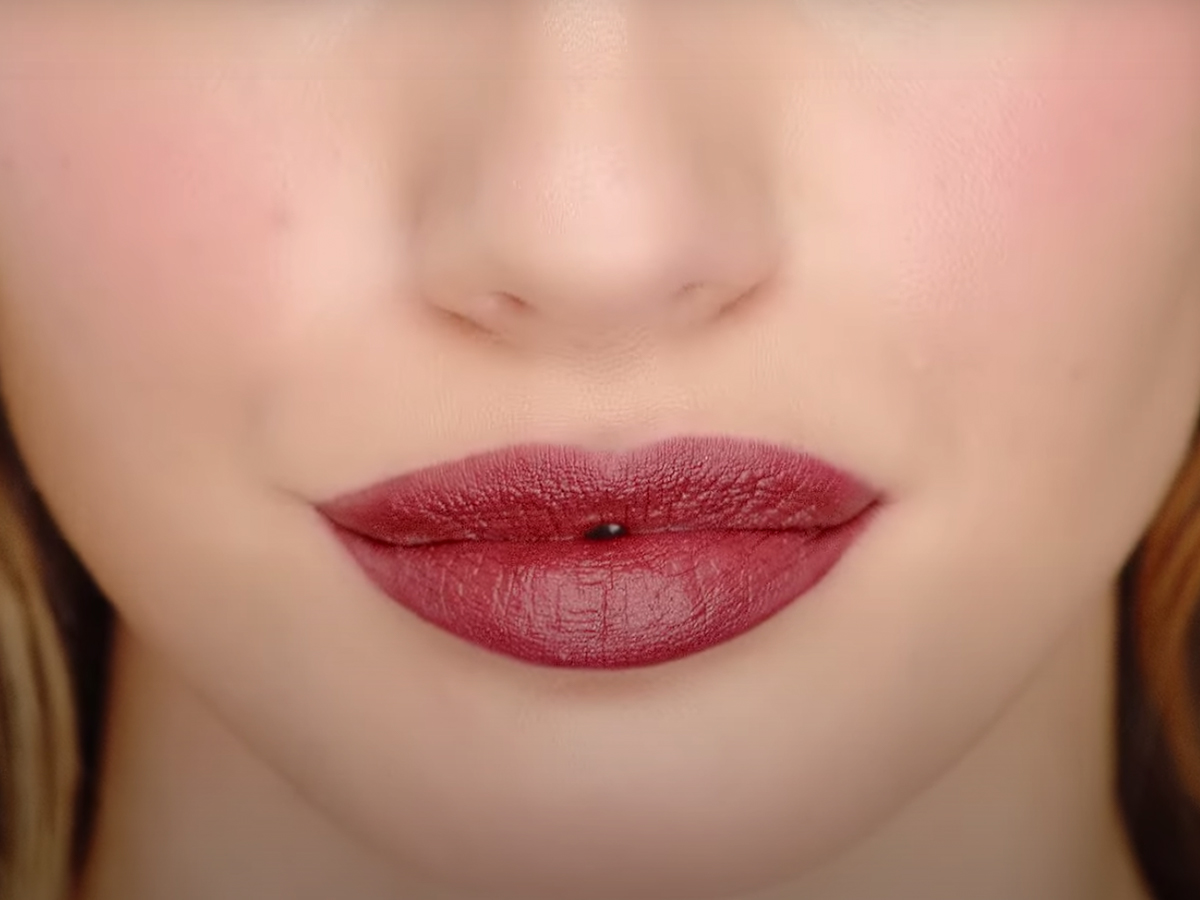 Lips close-up of a light-tone model wearing a berry-pink lipstick. 