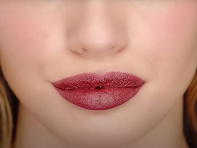 Lips close-up of a light-tone model wearing a berry-pink lipstick. 