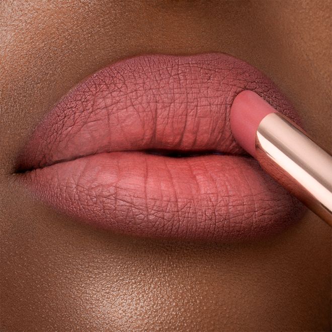 Limitless Lucky Lips in Rose Hope on deep-tone lips close-up Lips close-up of a deep-tone model applying a lipstick in a neutral rosy-pink colour with a matte finish.