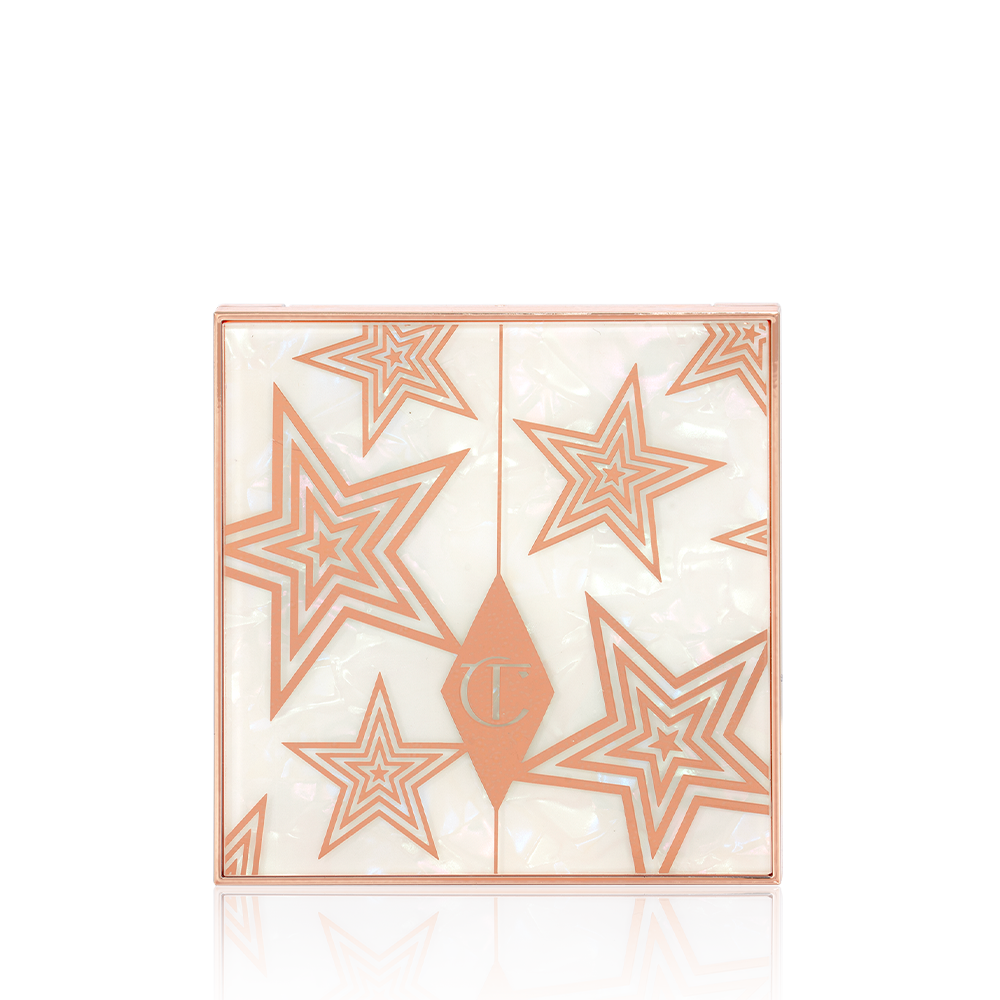 A closed eyeshadow palette with a pearly-white lid with gold stars printed all over. 