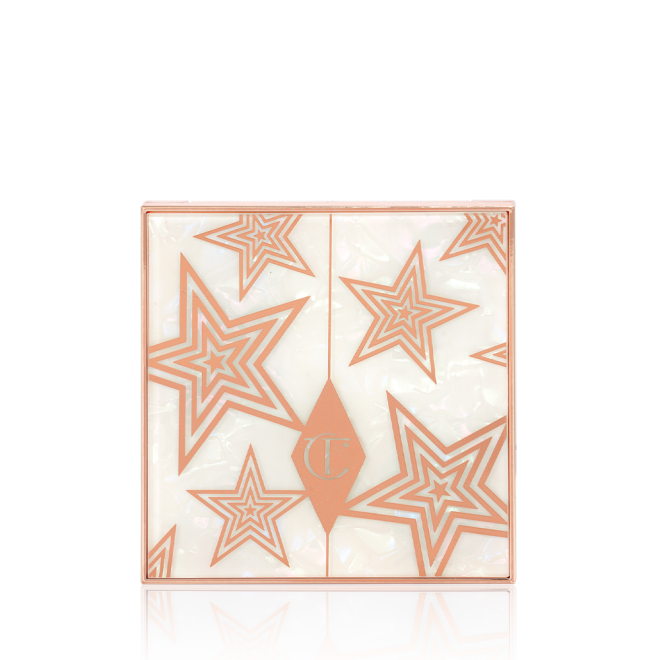 A closed eyeshadow palette with a pearly-white lid with gold stars printed all over. 