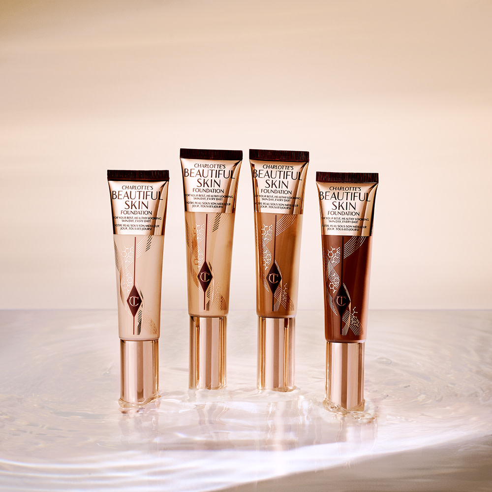 A collection of four foundation wands in packaging that display the colour of the foundation inside with sleek, gold-coloured lid.