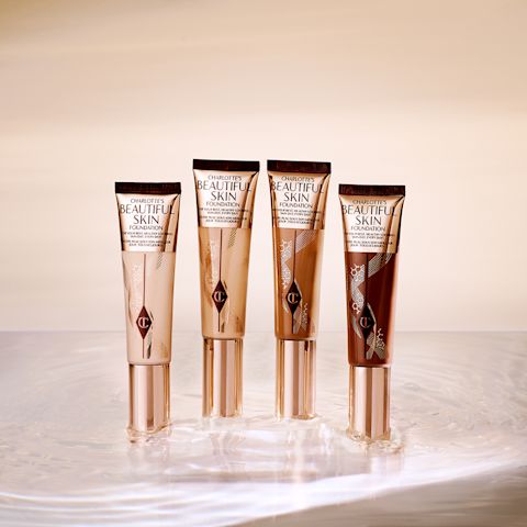 A collection of four foundation wands in packaging that display the colour of the foundation inside with sleek, gold-coloured lid.