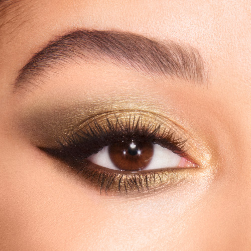Close-up of a light-tone model's brown eye with shimmery green, gold, and khaki eye makeup. 