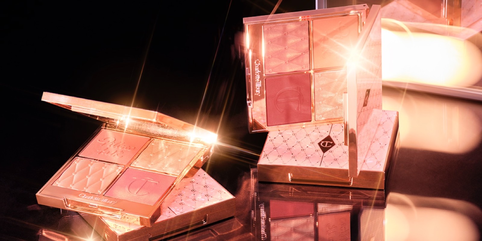 An open, face palette with matte and shimmery eyeshadows, blushes and highlighters in shades of pink and gold with a mirrored lid and a vivid pink eyeliner in gold packaging.