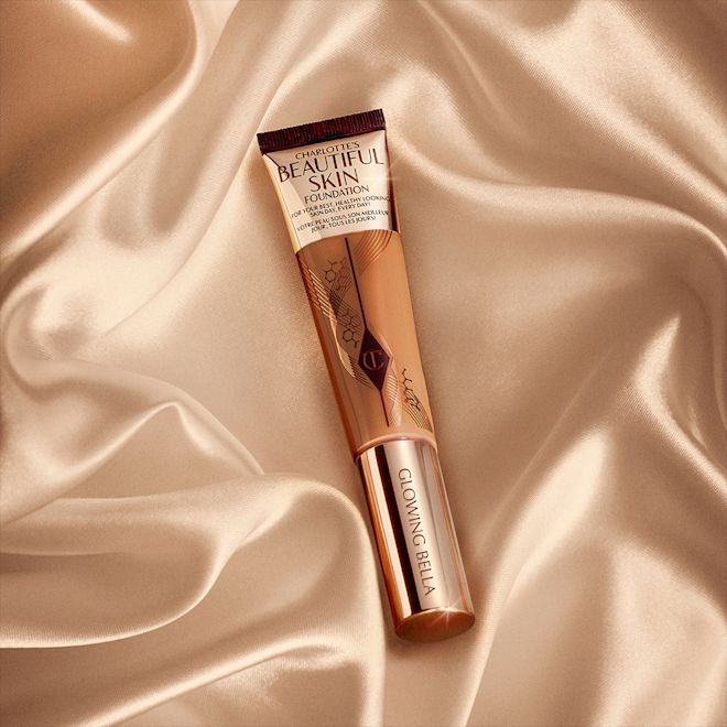 Beautiful Skin Foundation engraved banner A foundation wand in gold, engraved packaging with a medium-dark-brown-coloured body to show the shade of the foundation inside.