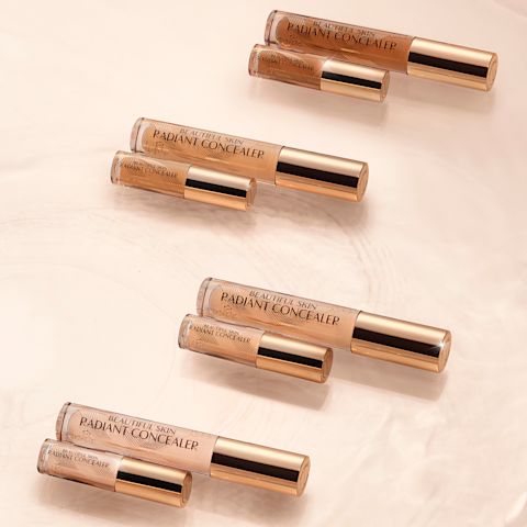 Collection of full-size and travel-size radiant concealers in a glass tubes with a gold-coloured lids with text on the tube that reads, 'Beautiful Skin Concealer'