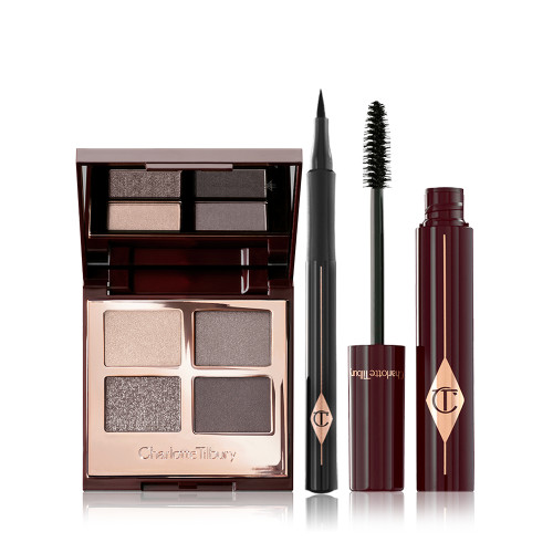 An open, quad eyeshadow palette in smokey grey shades with an open, black-coloured eyeliner pen, and an open mascara with its applicator in a dark-crimson colour scheme. 