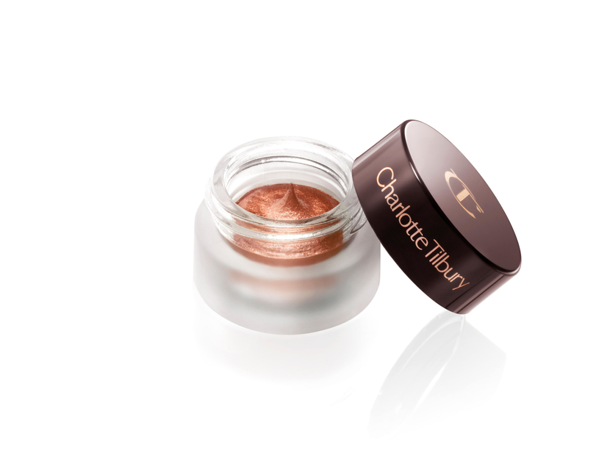 Russet rose cream eyeshadow with a golden-peach sparkle in a glass pot with the lid diagonally placed next on it.
