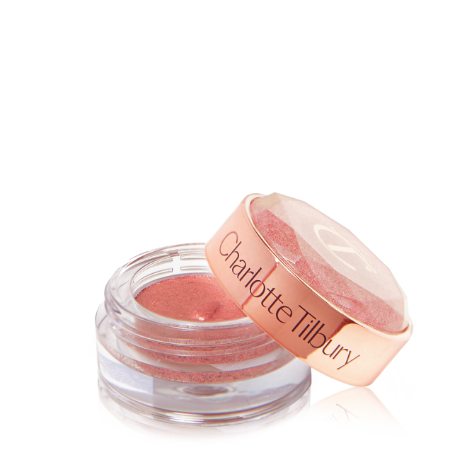 A shimmery eyeshadow pigment in a berry-pink shade in a glass pot with its lid next to it.