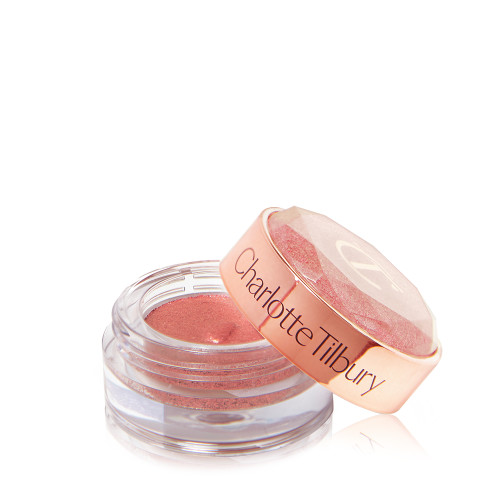 A shimmery eyeshadow pigment in a berry-pink shade in a glass pot with its lid next to it.