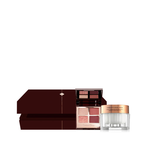 An open, dark brown mystery gift box with an open, quad eyeshadow palette with a mirrored lid with eyeshadows in shades of russet rose, dark brown, rose gold, and dull gold along with a white-coloured face cream in a glass jar with a gold lid next to it. 
